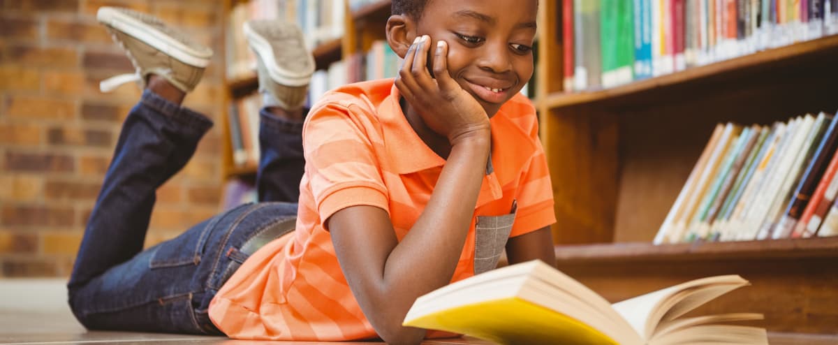 Cute boy reading book in library